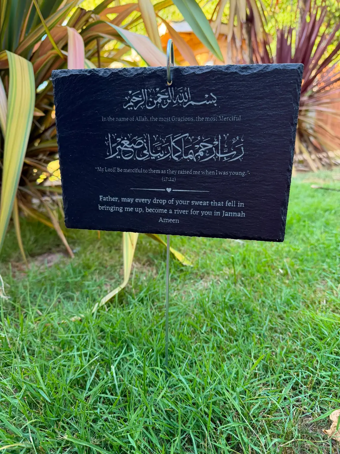In Loving Memory slate on its metal memorial plaque holder in a garden, engraved with the Bismillah, the supplication for parents (17:24) and a message to a father