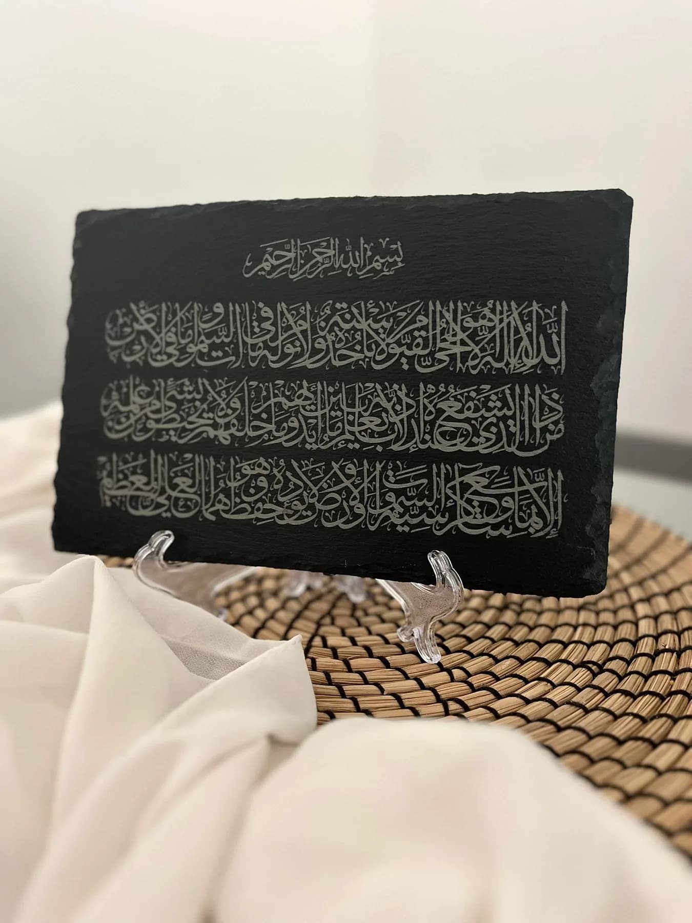 Ayat al-Kursi engraved in calligraphy on natural slate, displayed on a clear stand